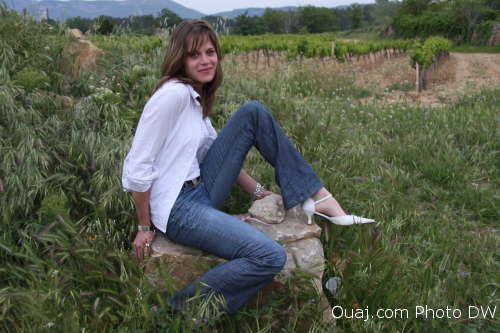 Manu assise sur 1 rocher devant un champ de vigne